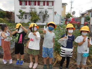 収穫した野菜を手に嬉しそうな1年生の子どもたちです