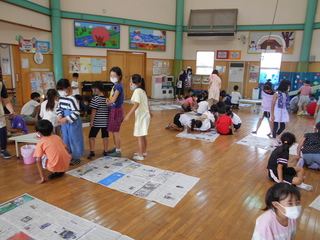 児童館ホールにてグループに分かれて新聞紙を貼り合わせている写真