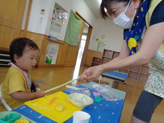 職員と粘土をひっぱりっこしている子どもの様子