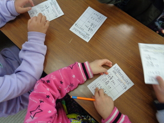 お正月あそびチャレンジカードに名前を書く子ども