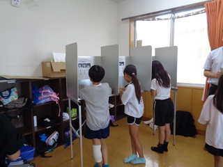 子どもたちが選挙の記入台で記入しているところ