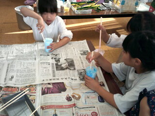 子どもたちがスライムに絵の具を入れているところ