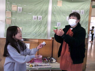 女児がお手玉のやり方を教えてもらっているところ