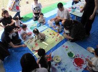 大きな紙に絵の具で自由に描いています。
